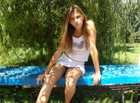 Young amateur crosses and uncrosses her legs on an outdoor bench 52443870