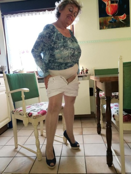 Old woman Caro pulls down her pantyhose in high heels at kitchen table 80569772