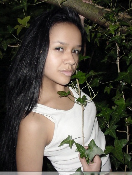 Pretty Indian girl hangs from a tree limb in a tank top and shorts 65844320