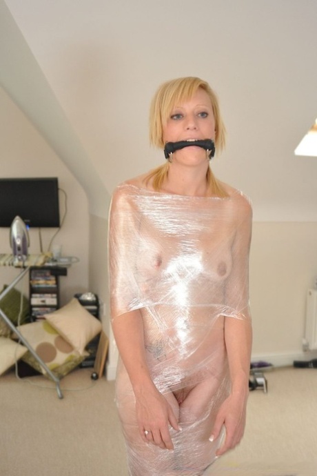 Fair skinned blonde is silenced with a gag while encased with plastic wrap 99809325