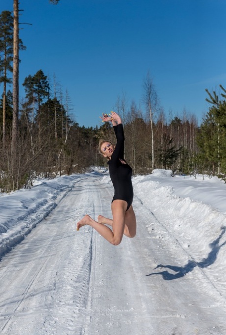 Blonde girl Claudia does the splits on a snow-covered road in bare feet 98185140